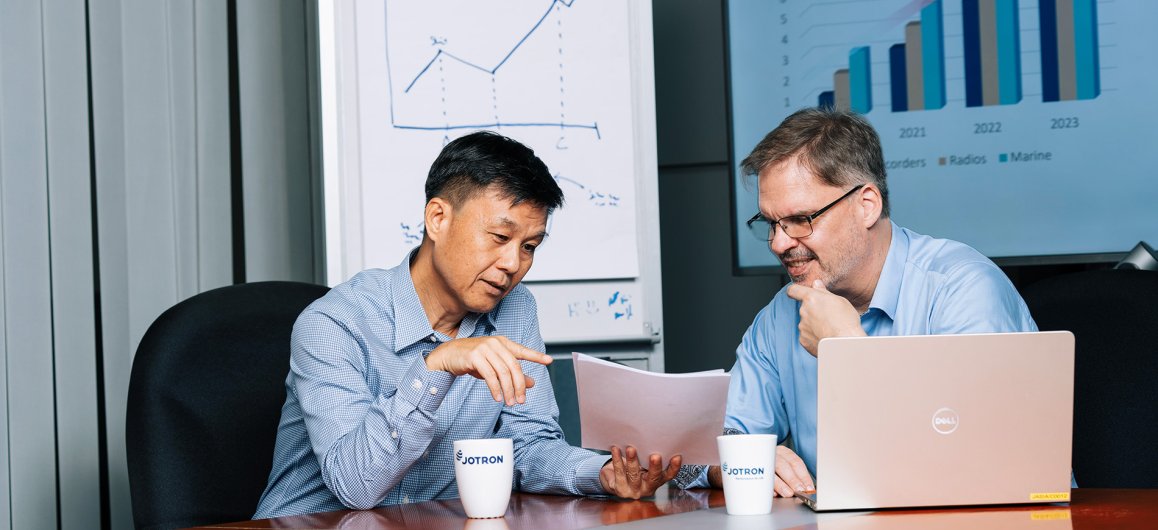 Two Jotron employees discussing in front of a laptop.