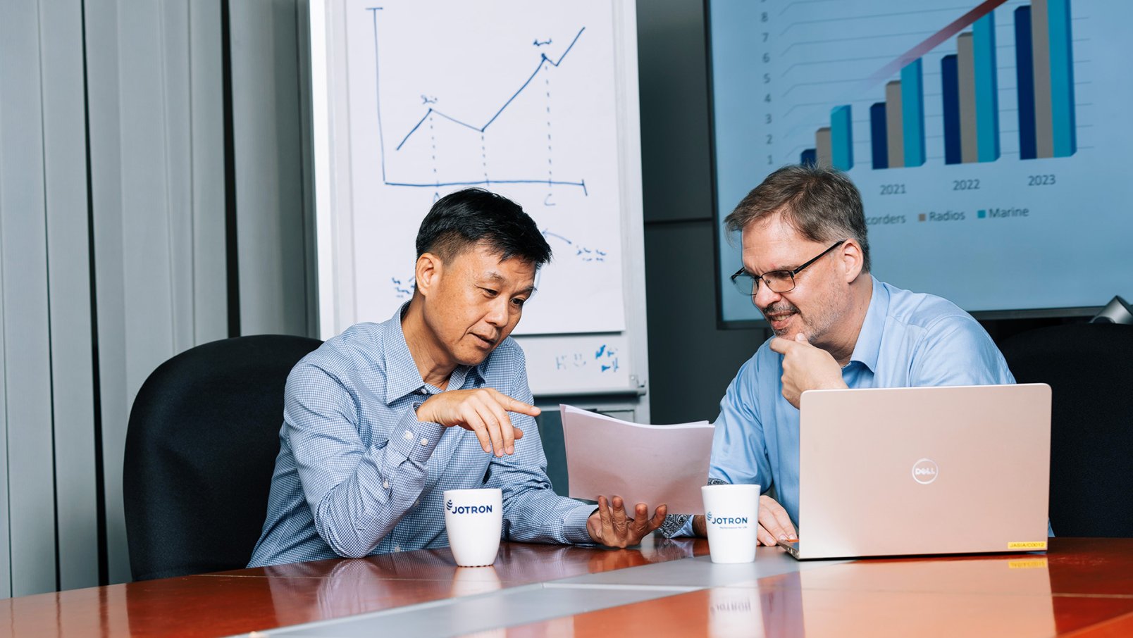 Two Jotron employees discussing in front of a laptop.