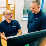 Two Jotron employees discussing in front of the PCs.