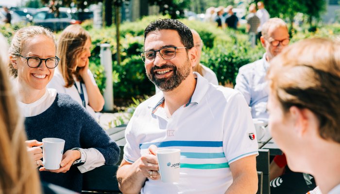 Jotron employees enjoying a coffee outdoors in the sun.