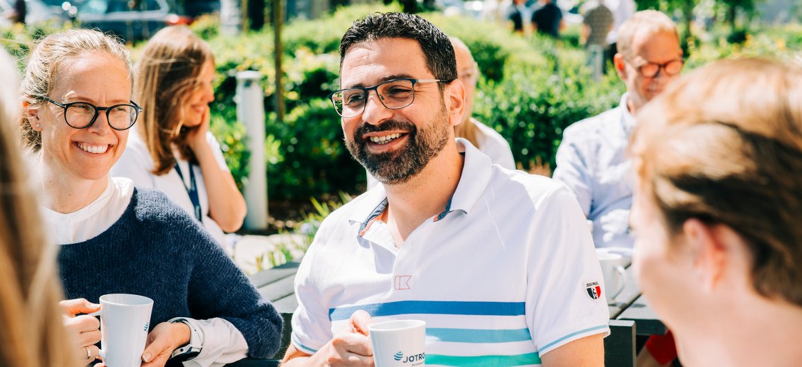 Jotron employees enjoying a coffee outdoors in the sun.