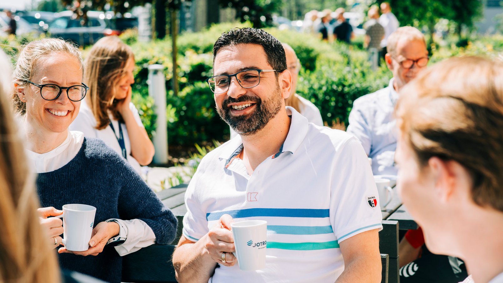 Jotron employees enjoying a coffee outdoors in the sun.