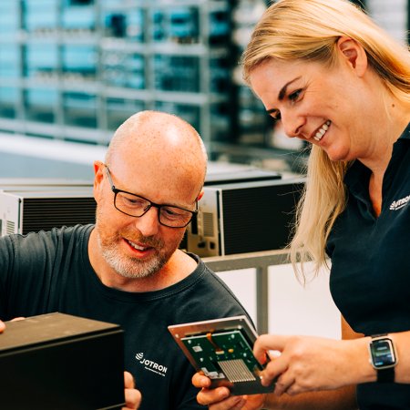 Two Jotron employees working in front of a PC. Two Jotron employees working in front of a PC.