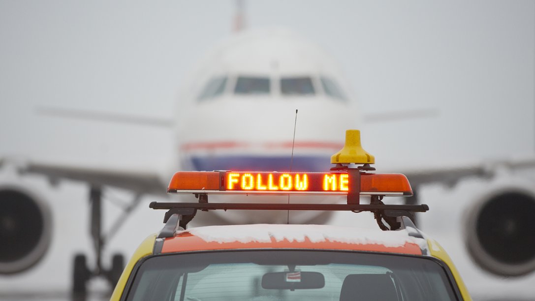 A follow-me car in front of an airplane.