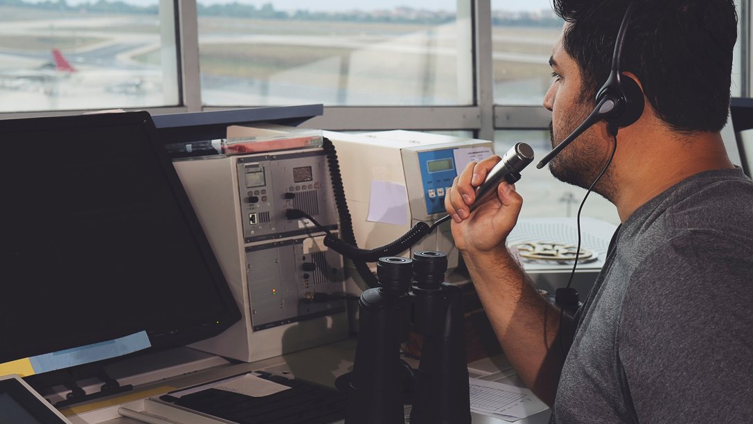 Air traffic controller in the ATC tower speaking in a microphone.