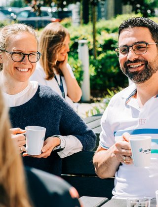 Two Jotron employees drinking coffee outdoors.