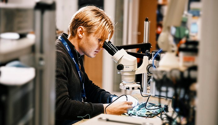 A Jotron employee looking into a microscope.