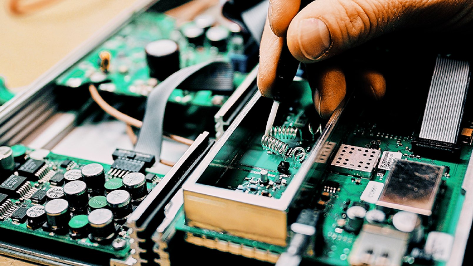 A hand soldering a circuit board.