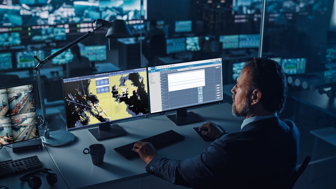 A port controller in front of monitoring screens.