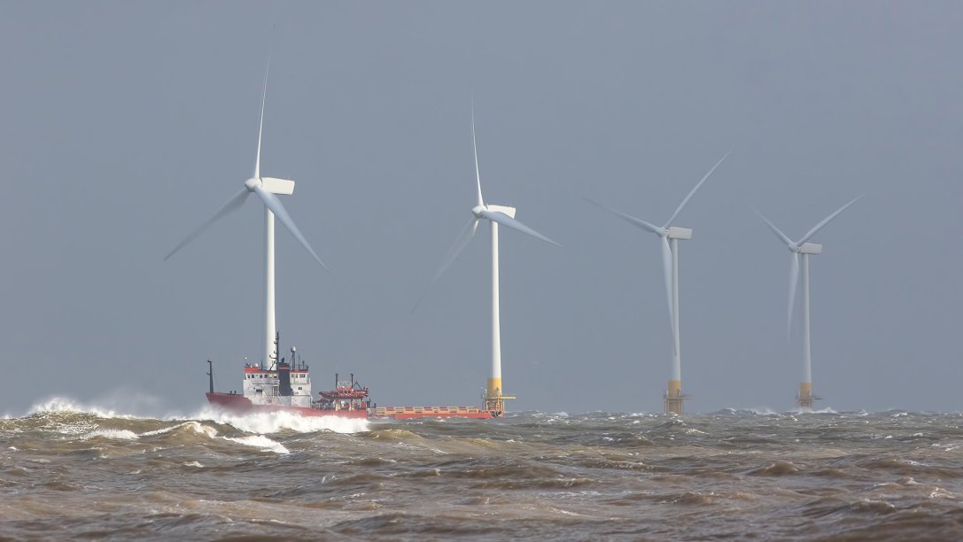 Safety standby, rescue, and maintenance vessel near an offshore wind farm turbine.