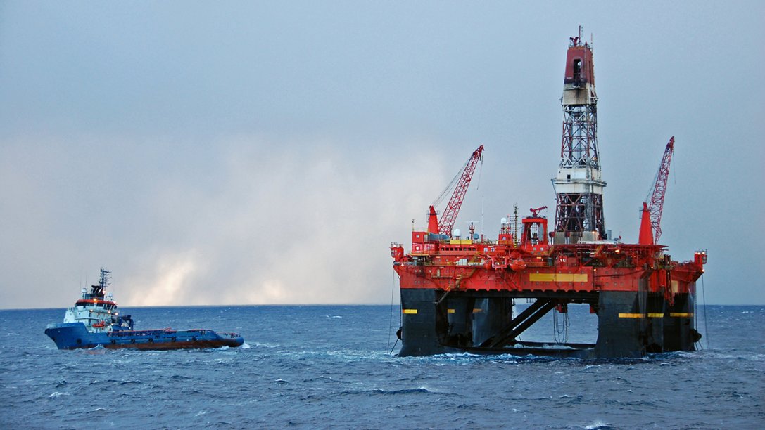 Supply boat and helicopter near an oil and gas platform.