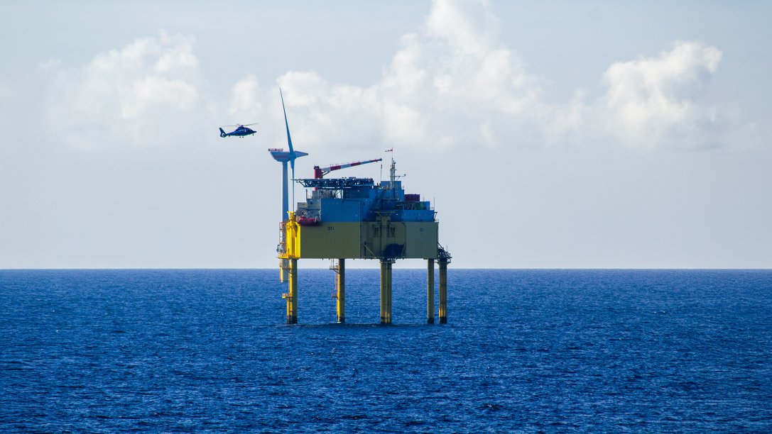  A helicopter approaching a transformer platform at an offshore energy wind farm.