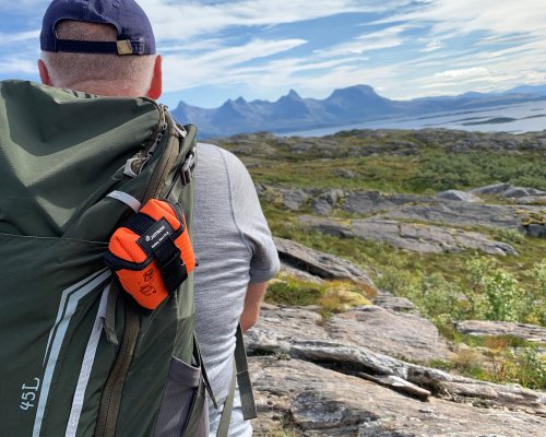 A man in mountain with PLB on his backpack.
