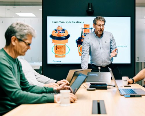 5 Jotron employees in a meeting room discussing EPIRB specifications.