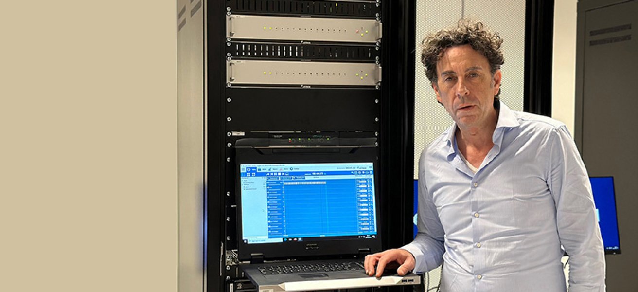 Nenad Jankovic standing in front of a Jotron ATC product rack, showing Ricochet Recorder software on the screen display.