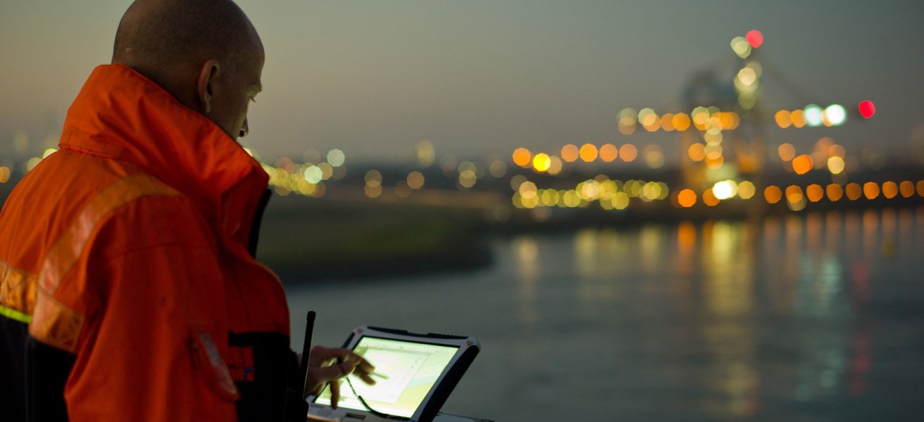 Maritime pilot navigating on deck using a screen.