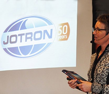 Merete Berdal in front of Jotron's logo, marking 50 years of business.