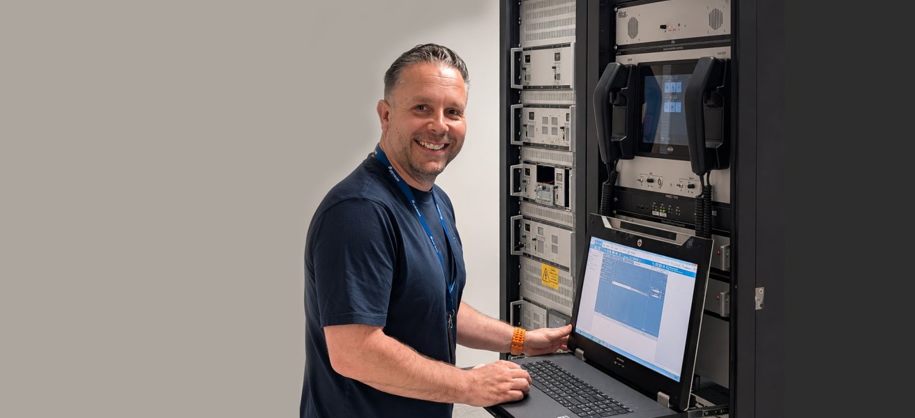 Jotron Product Manager for Ricochet Recorder standing in front of a ATC radio and recorder rack.