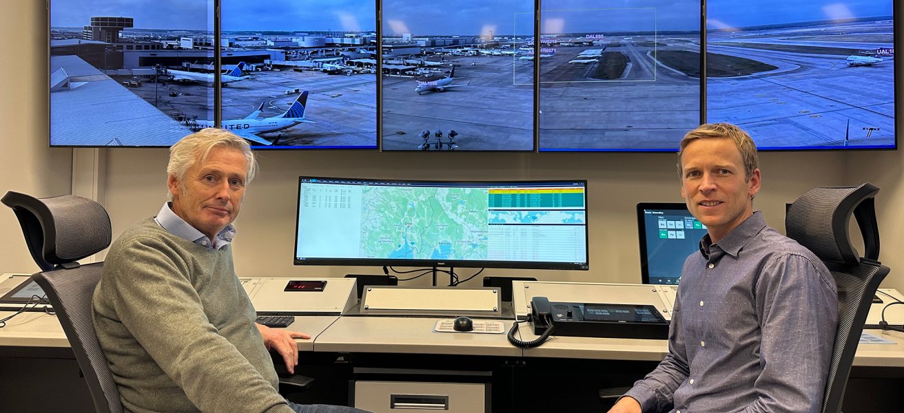 Two Jotron employees in front of air traffic control screens.