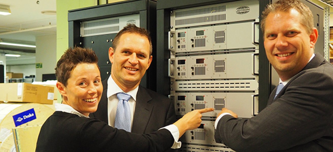 Jotron employees standing in front of a ATC radio rack.