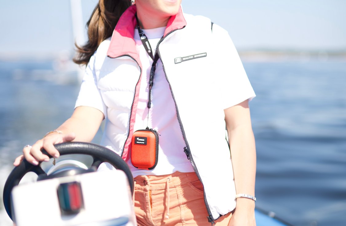 A sailor aboard a sailboat wears a Tron SA20 PLB around her neck.