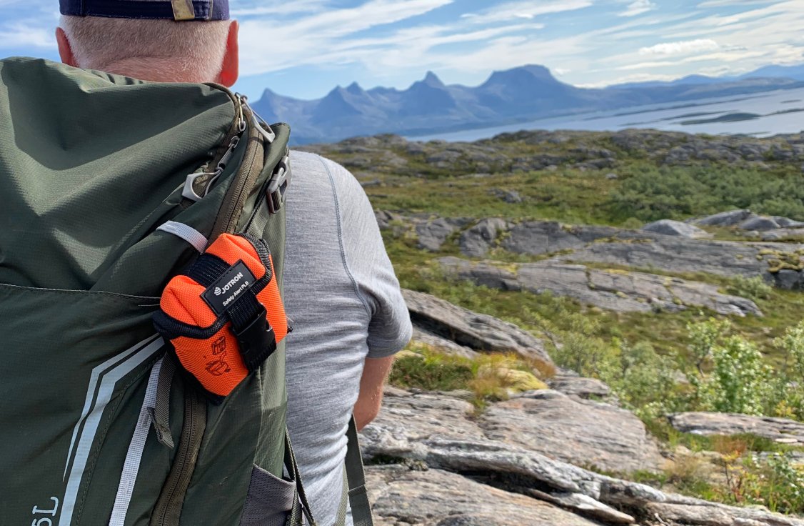 A man in mountain with PLB on his backpack.