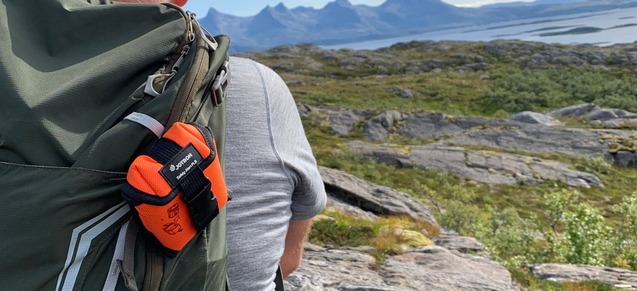 A man in mountain with PLB on his backpack.
