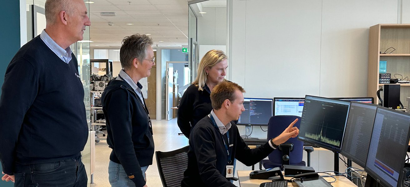4 Jotron employees in front of a PC looking at the screen